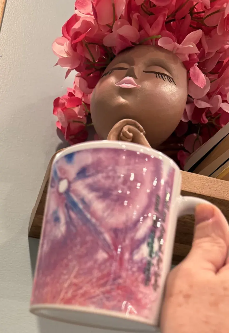 Ceramic face sculpture with pink petals holding a pink-toned mug for a spiritual art browsing hub